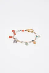 Pulsera de doble tira dorada combinada con cuentas de perlas y dijes colgantes de piedras naturales de colores, resina y perla barroca. Incorpora cierre de mosquetón con cadena de alargue.
