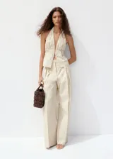Pantalón de vestir de tiro medio con diseño de rayas verticales en tono beige y crudo. Presenta pernera recta y holgada, con pinzas delanteras y bolsillos laterales.