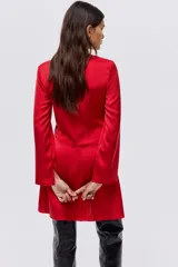 Vestido corto de color rojo, con escote redondo y detalle girado en el frente. Presenta mangas largas con abertura en los puños, falda con leve vuelo y cierre oculto en la espalda.