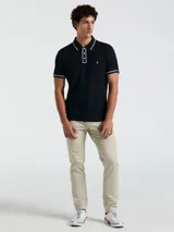 Polo de piqué azul marino con vivos blancos en cuello y mangas, calce slim fit y logo bordado en el pecho.
