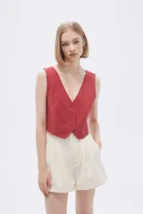 Top tipo chaleco de corte entallado, con escote en V y cierre frontal con botones a tono.
