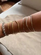 Pulsera rígida de metal con tres aros irregulares, disponible en alpaca color plateado o bronce color dorado.