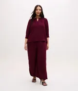Blusa de crepé bordó con mangas 3/4, escote redondo con abertura en V y detalles fruncidos en el cuello.