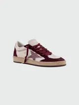Zapatillas de estilo urbano con diseño desgastado, combinan paneles de cuero blanco y gamuza en color bordó. Presentan una estrella lateral con acabado brillante, cordones al tono y suela de goma con efecto envejecido.