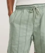 Bermuda recta de playa en color blanco roto, confeccionada en algodón texturizado con efecto de rayas verticales. Posee cintura elástica con cordón ajustable.