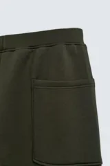 Pantalón de corte wide fit confeccionado en tejido técnico con efecto neopreno. Presenta cintura elástica ajustable con cordón, perneras anchas con costura frontal, bolsillos laterales y bolsillos traseros de plastrón.
