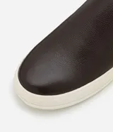 Championes tipo slip-on de cuero marrón con detalle de talón en tono contrastante y suela de goma blanca.