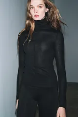 Jersey de punto con lana, de cuello subido y manga larga. Presenta un diseño ajustado con detalle de costuras verticales marcadas en el frente.