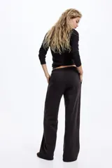 Pantalón tipo jogger de corte holgado y pierna ancha, confeccionado en felpa con interior suave. Presenta cintura elástica con cordón ajustable y bolsillos laterales discretos.