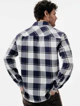 Camisa de manga larga con estampado de cuadros en tonos azul marino y blanco. Presenta cuello clásico, cierre frontal con botones y dos bolsillos con solapa en el pecho.