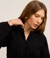 Blusa tipo bata confeccionada en voile color negro, con cuello padre con botones en la vista, recorte V en el busto y mangas largas.