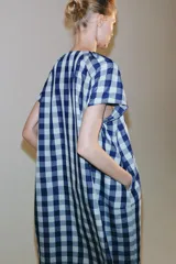 Vestido midi de Zara Woman Collection confeccionado en mezcla de viscosa, con estampado de cuadros en tonos azul y celeste. Presenta cuello redondo, manga corta, bolsillos ocultos en las costuras y cierre frontal con cordones entrelazados.