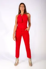 Body de color rojo con escote halter y detalle de herrajes metálicos dorados en los hombros. Presenta un diseño drapeado en el frente y cierre inferior.