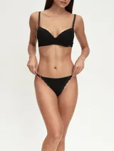 Colaless de tiro bajo color negro, con bordes de encaje floral en la parte delantera y trasera. Los laterales son tiras finas ajustables con argollas metálicas.