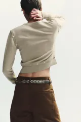 Jersey de punto con cuello en V y manga larga. Presenta un diseño versátil con detalles de acabados desmontables mediante botones en la parte inferior y en los hombros.