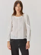 Camisa de algodón con diseño de broderie floral, cuello redondo y mangas largas abullonadas con volados en los hombros y puños elásticos.