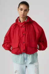Campera parka roja estilo blouson con capucha ajustable, cierre frontal de botones a presión, bolsillos frontales con solapa y diseño holgado.