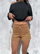 Short de tiro alto confeccionado en tela tipo gamuza scuba, con detalle de cordones frontales cruzados y ojales metálicos. Presenta un diseño ajustado y elástico que se adapta a la silueta.