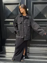 Campera clásica de jean negra con cuello camisero, bolsillos frontales y detalles de brillos plateados.