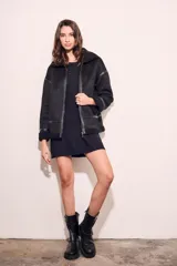 Campera tipo gamulán de corte oversize, color negro, con interior y cuello de corderito sintético. Presenta cierre frontal, detalles de costuras y puños con terminación en corderito.