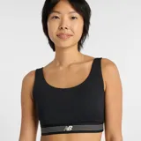 Top deportivo de alto rendimiento con diseño de escote redondo y espalda estilo nadadora. Presenta una banda elástica inferior con rayas horizontales y el logo de la marca. Confeccionado en tejido técnico transpirable de secado rápido, ideal para actividades de impacto moderado. Incluye copas extraíbles.