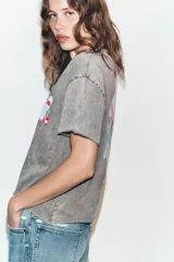Camiseta oversize de algodón con efecto lavado en color gris, cuello redondo y manga corta. Presenta un estampado gráfico pequeño en el pecho con diseño de nube y cereza.