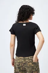 Remera blanca de punto acanalado, corte ajustado, mangas cortas raglán y ruedo ondulado.