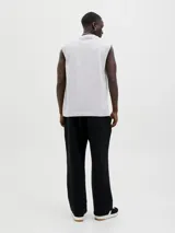 Musculosa blanca de algodón con cuello redondo y estampado de dos círculos entrelazados con líneas horizontales en tonos naranja, celeste y azul.