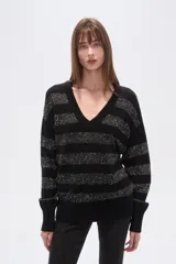 Sweater negro con cuello en V, diseño holgado y mangas largas. Presenta rayas horizontales de lentejuelas plateadas.
