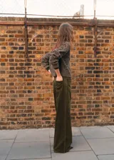 Jeans wide leg tiro alto de pana color verde militar, con diseño de cinco bolsillos, trabillas y cierre frontal con botón y cremallera.