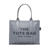 Bolso tote grande de cuero granulado color gris azulado, con asas superiores y estampado frontal en negro que dice "THE TOTE BAG MARC JACOBS".