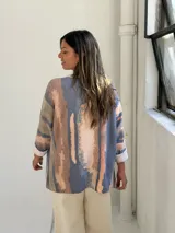 Sweater de tejido de punto con diseño abstracto en tonos azul, beige y rosado, de corte holgado y mangas largas con puños vueltos.