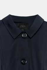 Blazer corta de color azul marino, con cuello solapa y cierre frontal con botones. Cuenta con manga larga con frunces en los hombros.