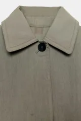 Trench oversize de Zara Woman Collection, confeccionado en hilatura de algodón. Presenta cuello solapa, manga larga, bolsillos delanteros y cierre frontal con botones ocultos bajo solapa.