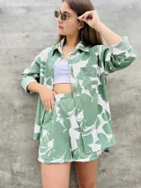 Camisa verde con estampado de hojas blancas, de corte holgado, manga larga y cuello camisero.