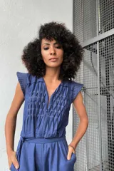 Mono negro de lino y algodón texturizado con plisados de pespuntes de color en contraste. Tiene lazo en la cintura y fuelle en la espalda.