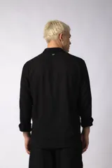 Camisa de manga larga con cuello clásico y cierre frontal de botones. Presenta un calce relajado y una textura liviana.