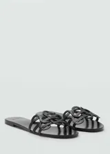 Sandalias planas de cuero color negro, con diseño de tiras entrelazadas en la capellada, estilo destalonado.