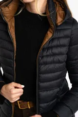 Campera reversible con diseño acolchado, cierre frontal y capucha. Un lado es de color negro y el otro de color tostado, con puños tejidos en color negro.