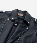 Campera estilo biker confeccionada en poliuretano con base de viscosa, forrada en poliéster. Presenta cuello con solapas, cierre frontal con cremallera metálica, bolsillos laterales con cierre y detalles de botones a presión.