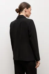 Blazer clásico color negro de corte entallado, con solapa de muesca, cierre de un botón frontal y bolsillos de ojal en los laterales.