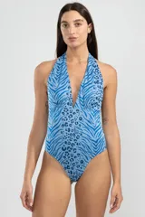 Traje de baño enterizo con estampado animal print en tonos de azul, con escote halter y espalda descubierta.