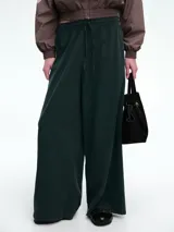 Pantalón de corte holgado y pierna ancha, confeccionado en pana color marrón. Presenta cintura elástica con cordón ajustable y diseño de tiro medio.