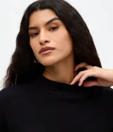 Blusa de manga corta amplia y sisas desplazadas, confeccionada en punto leve de viscosa y poliamida, con cuello redondo ligeramente alto.