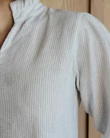 Blusa de algodón color azul, de corte suelto, con mangas largas abullonadas y cuello con volados y escote en V.