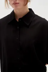 Camisa de lino blanca de corte holgado, con cuello camisero y mangas tres cuartos, diseñada con estilo casual.