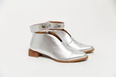 Botín de cuero color borgoña con taco bajo, corte en V en el empeine, pulsera con detalles metálicos y cierre lateral.