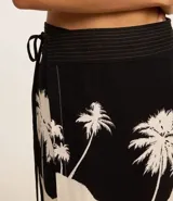 Pollera corta de playa confeccionada en viscolino con viscosa certificada. Diseño cruzado con cintura ancha y estampado de palmeras.