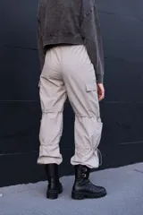 Pantalón cargo color beige con bolsillos laterales, cintura elástica y cordones ajustables en las rodillas y los tobillos.
