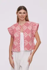 Chaleco corto con estampado geométrico en tonos rosa y rojo, sin mangas y cuello redondo.
